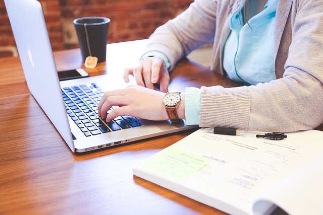 A focused person sitting at a desk, engrossed in their work on a laptop